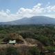 The pyramid, known as the Campana structure, with volcanic mountains in the background.